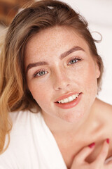 Wall Mural - Beauty portrait of natural, calm, young woman with freckles on her face. Serene people. Girl with delicate smile looking at the camera. Ideal eyebrows and lashes. Skin care concept. Morning light.