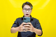 overjoyed young asian man with peek a boo colored hair wearing black shirt holding phone. Young Asian man with a pleasing smile using a smartphone for trading or chatting.