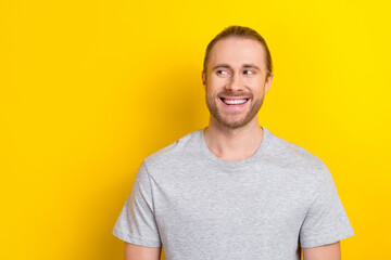 Wall Mural - Photo of dreamy cheerful guy dressed grey t-shirt looking empty space isolated yellow color background