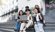 © wichayada - Group of cheerful Asian college students sitting on stairs, showing fists, celebrating triumph