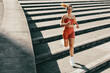 Athletic female using music to enhance running and jogging outdoor stairs workout
