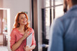 © kerkezz - Cheerful businesswoman holding laptop and chatting with colleague on break.