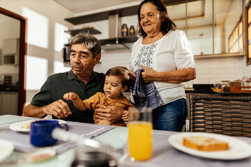 Wall Mural - Happy grandparents having breakfast with their grandson