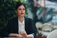 Stylish Fashion Woman Portrait Sitting In A Cafe At A Table And Smoking A Cigarette Releasing Smoke From Her Mouth With Red Lipstick, Bad Habit, Smile With Teeth And Pensive Look, Cinematic Vintage