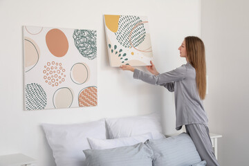 Wall Mural - Young woman hanging painting on light wall in bedroom