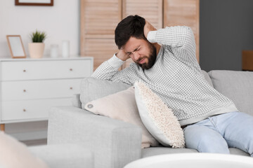 Wall Mural - Young man suffering from loud noise at home