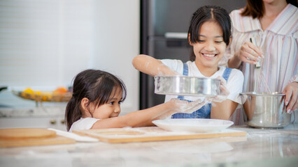 Two little cute Asian girls, learning how to make bread and bakery with a curious and happy smile face. She learns and plays