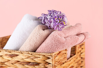 Wall Mural - Wicker basket with folded soft towels and hyacinth flower on pink background