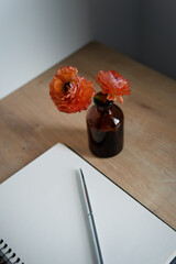 Wall Mural - opened by a block with a pen and a flower on a wooden table close-up.