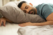 © Home-stock - Portrait of peaceful european man sleeping in bed at home, lying with hand under pillow, resting with closed eyes. Healthy, good sleeping