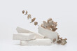 © Liliia - Stack stones platform podium and eucalyptus leaf twig on gray light copy spase background. Minimal empty display product presentation scene.