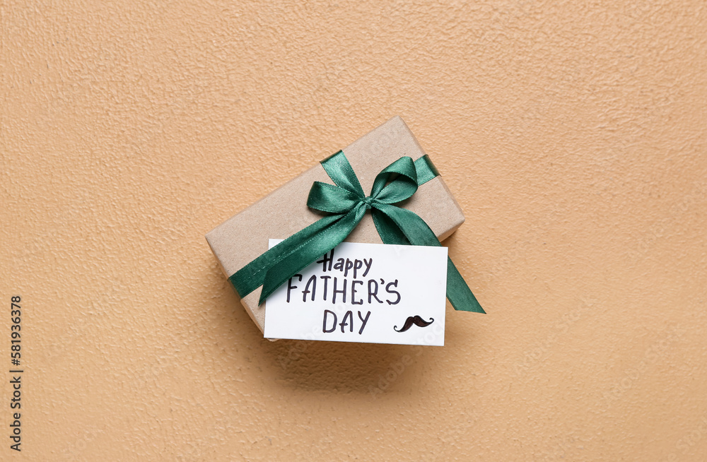 Paper with text HAPPY FATHER'S DAY, drawn mustache and gift on beige background