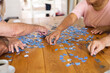 © Wavebreak Media - Hands of diverse senior friends sitting at table doing jigsaw puzzle together