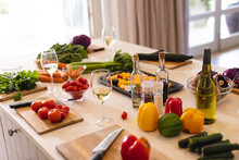 Fresh Vegetables And Seasonings On Table In Kitchen With Bottle And Glasses Of White Wine