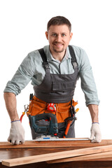 Wall Mural - Male carpenter measuring wooden plank at table on white background