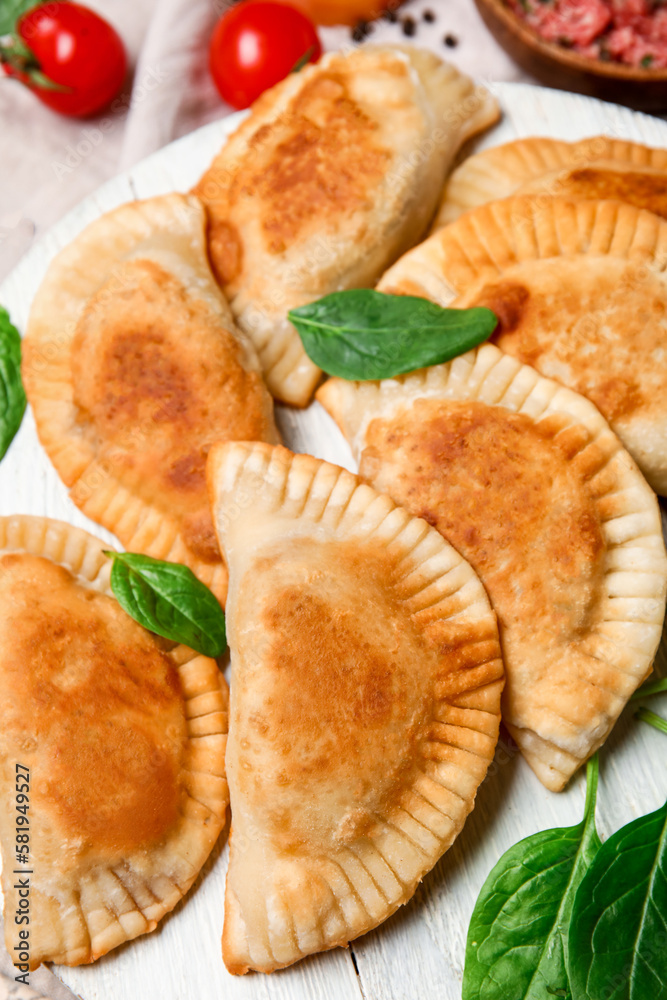 Wooden board with tasty meat empanadas, closeup