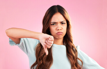 Sticker - Upset, thumbs down and portrait of a female in a studio with a sad, moody or disappointed face. Loser, unhappy and young woman model posing with a angry hand gesture isolated by a pink background.