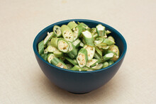 Close-up Of Sliced Raw Okra In Blue Ceramic Bowl On White Background