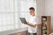 © Anciens - Asian man is using laptop near the window.