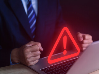 Wall Mural - businessman using laptop showing warning triangle and exclamation sign icon caution of dangerous pro