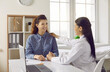© Studio Romantic - Cheerful redhead Caucasian woman uses services of female doctor with smile looks at therapist holding hand and thanks for treatment under medical insurance sits at table with laptop in private clinic