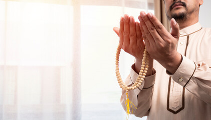 Muslim islam man in brown session lift two hand for praying ,isolated on light beige background.