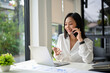 © bongkarn - Attractive Asian businesswoman talking on the phone with her business partner, dealing business