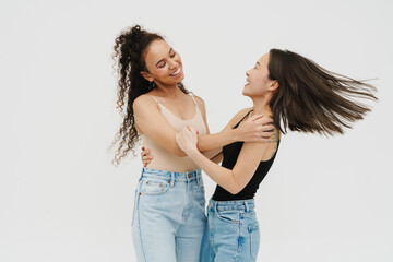 Two carefree girls having fun together isolated over white wall