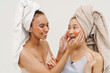 © Drobot Dean - Two women applying hydrogel eye patches after shower isolated over white wall