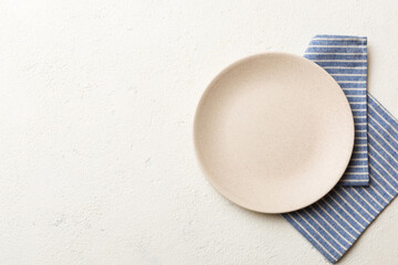 Top view on colored background empty round white plate on tablecloth for food. Empty dish on napkin with space for your design
