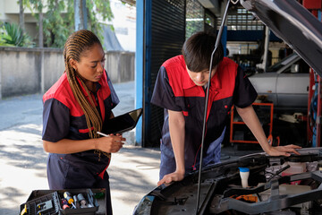 Two professional automotive mechanical partners check and repair an EV car battery and hybrid engine at a maintenance garage, expert electric vehicle service, and fixing occupations auto industry.