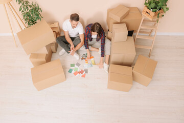 Canvas Print - Happy couple surrounded by moving boxes choosing colors in new apartment, above view