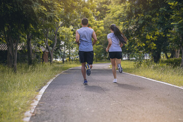 Canvas Print - Silhouette of young couple running together on road. Couple, fit runners fitness runners during outdoor workout with sunset background.
