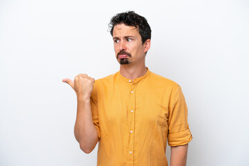 Wall Mural - Young man with moustache isolated on white background unhappy and pointing to the side