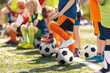 © matimix - Group of Children With Football Soccer Balls at Training Class. Outdoor Football Training For Little School Kids. Boys and Girls Having Fun at Sports Practice on Summer Day