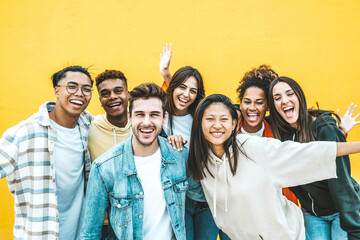 Multiracial group of young people standing in front of yellow isolated background - Youth community concept with guys and girls laughing looking at camera - Bright colors