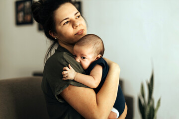 Wall Mural - Loving mother taking care of her newborn baby at home. Mother's Day Concept