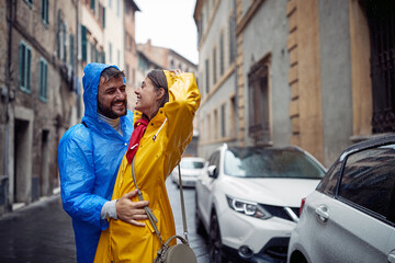 Wall Mural - A young happy couple enjoying a rain while walking the city. Walk, rain, city, relationship