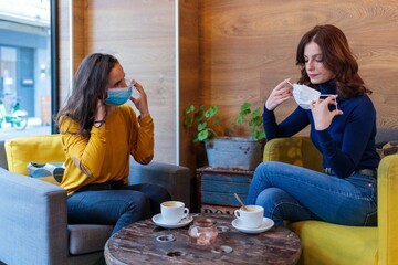 Caucasian women sitting in a cafe and wearing face masks