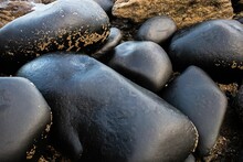 Close-up Of Black Stones On A Sandy Beach