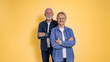 © Moon Safari - Portrait of cheerful loving senior couple dressed in denim shirts posing together with arms crossed while standing isolated on yellow background