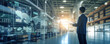 © Bartek - A businessman stands in front of a massive warehouse facility while holding a virtual interface panel for the world's logistics network for distribution and transportation.  - Generative AI