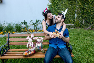 Wall Mural - Couple with easter bunny ears in garden, colorful easter eggs