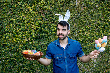 Wall Mural - man with easter bunny ears holding colored easter eggs