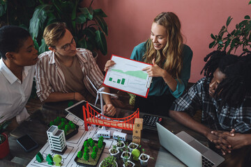 Diverse group of international students working on the urban project of modern city with renewable energy source, green areas. Concept of ecology, environment protection, waste recycling, technology