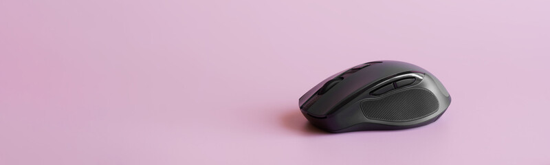 black computer mouse with a scroll wheel, additional buttons and a rubber pad on a pink background. 