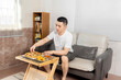 © Anciens - Asian man is eating pizza in the living room.