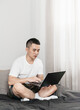 © Anciens - Asian man is using laptop on the bed in bedroom.
