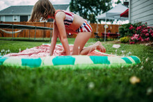 Young Girl Getting Off Slip And Slide In Back Yard