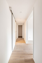 White corridor with entrances to bright room and slide doors in an empty apartment before moving or after renovation. Concept of renovation and restoration of old premises. Copyspace